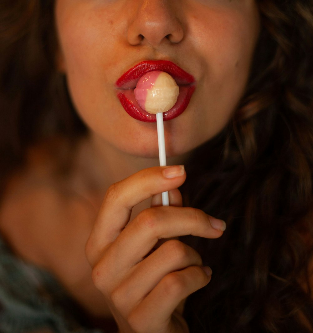 woman with red lipstick holding red lollipop