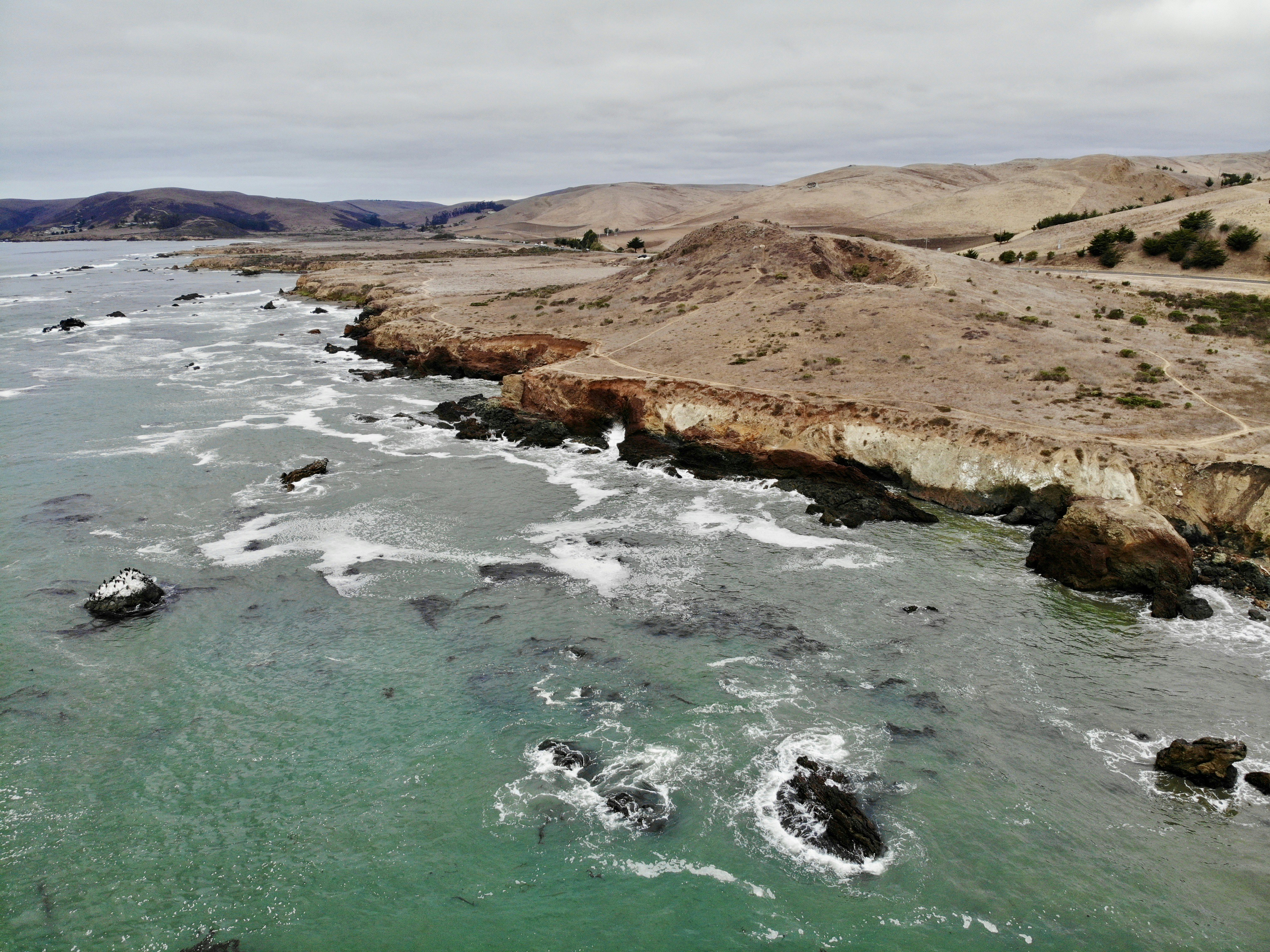brown and green mountain beside body of water during daytime