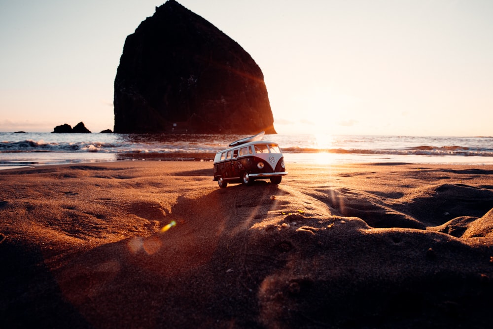 black car on beach near brown rock formation during daytime