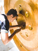 Close-up of bronze gongs shimmering under soft light, showcasing intricate Balinese carvings.