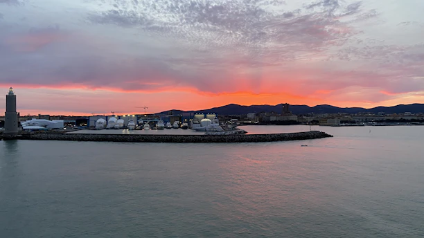 A vibrant sunset over the coastline of Touros with colorful boats docked at the pier.