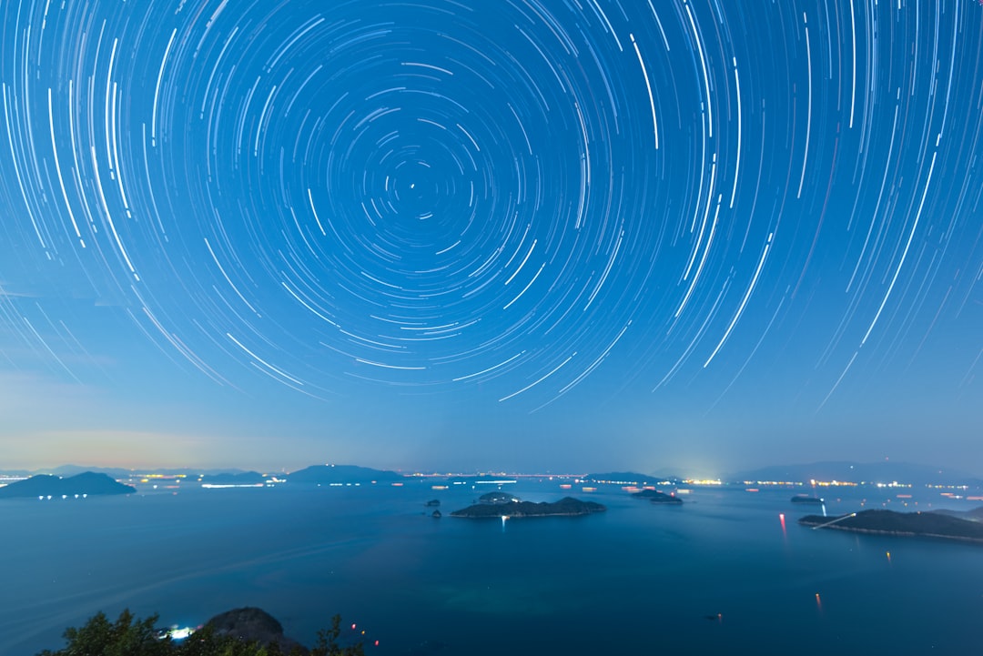 time lapse photography of stars above body of water during night time