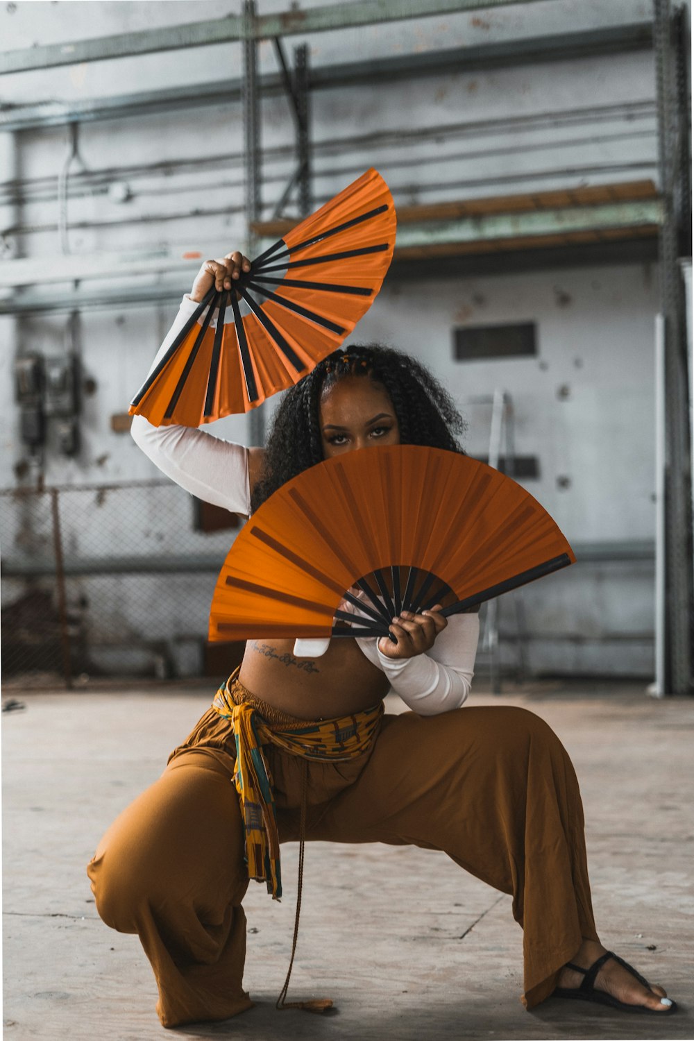 woman in white long sleeve shirt and brown skirt sitting on concrete floor holding umbrella