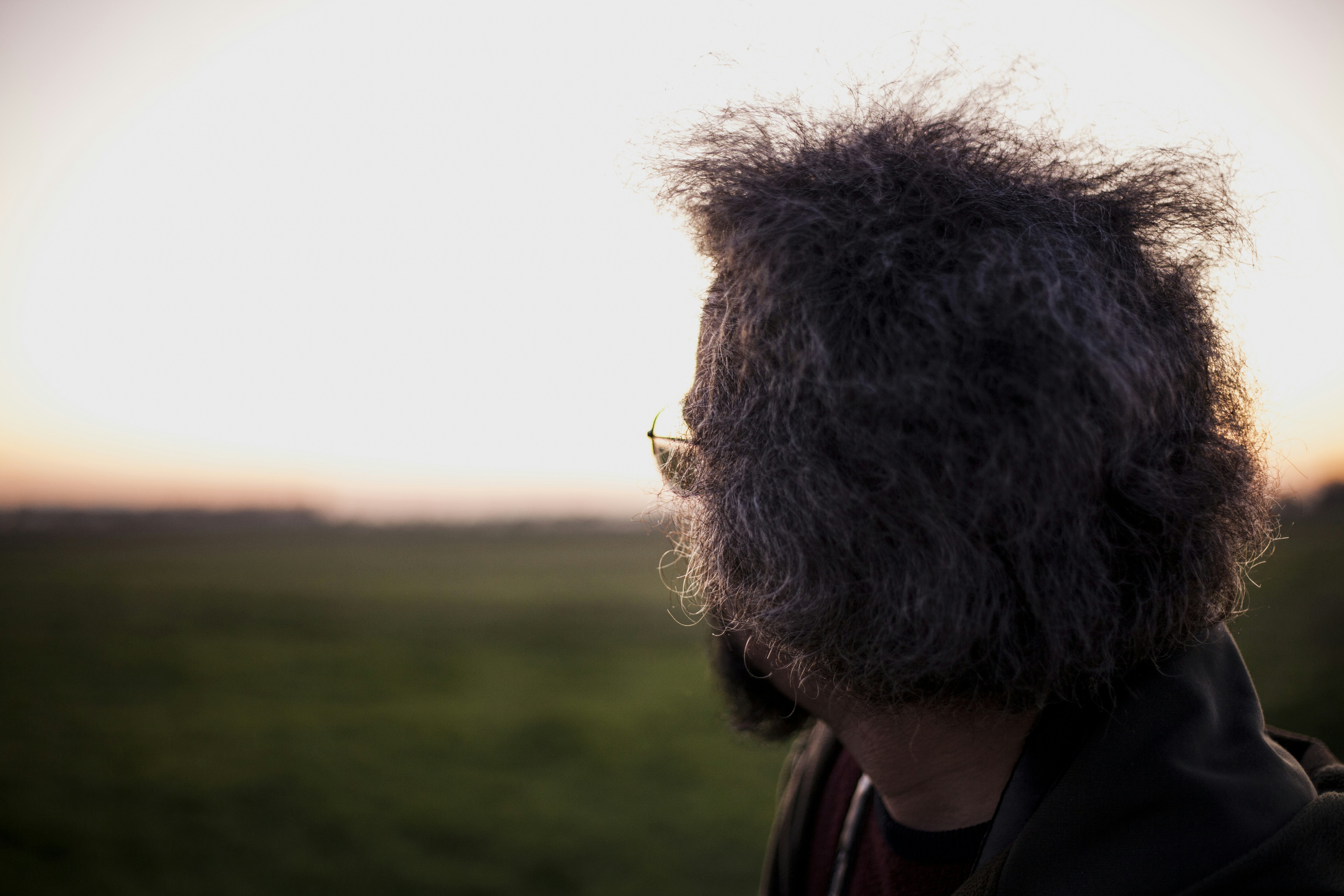 man in black and brown jacket standing on green grass field during daytime