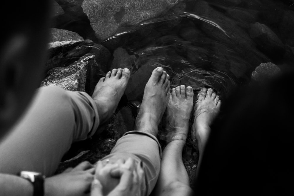 grayscale photo of persons feet on water
