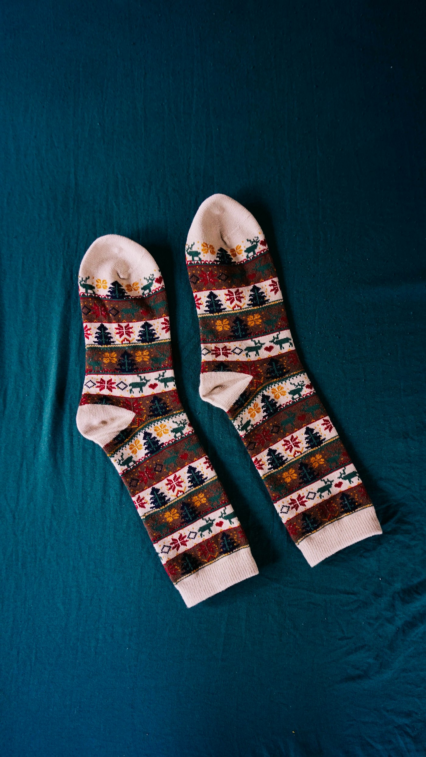 A pair of premium patterned knit amenity socks laid flat on a deep navy backdrop