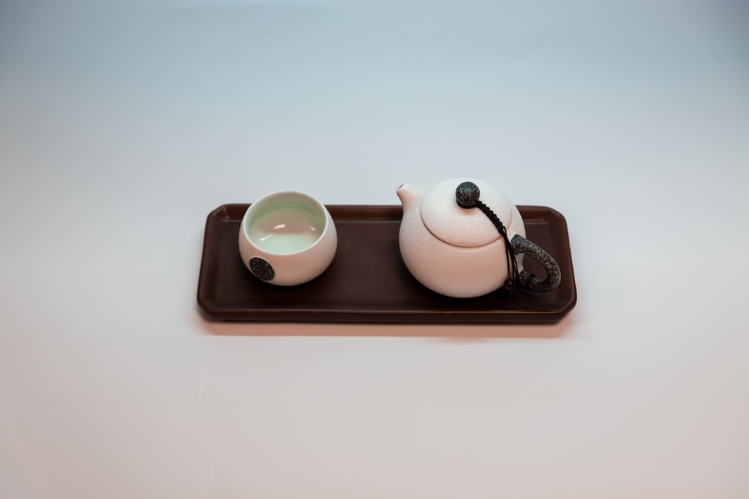 white and brown ceramic teapot on brown tray