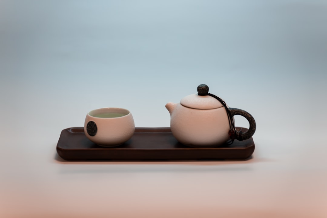 white ceramic teapot and teacup on brown wooden tray