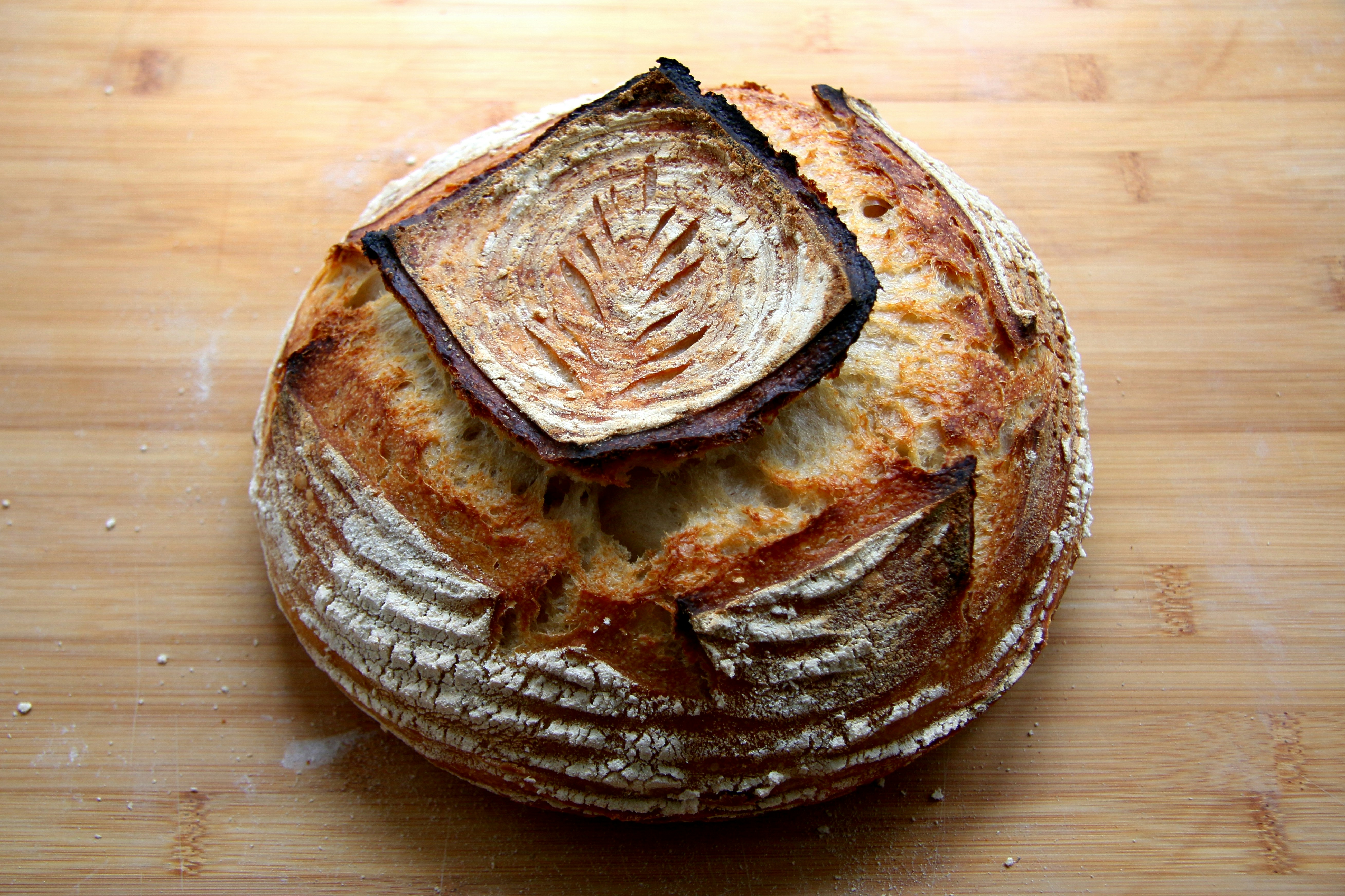 Golden sourdough bread loaf with scored pattern on wooden board