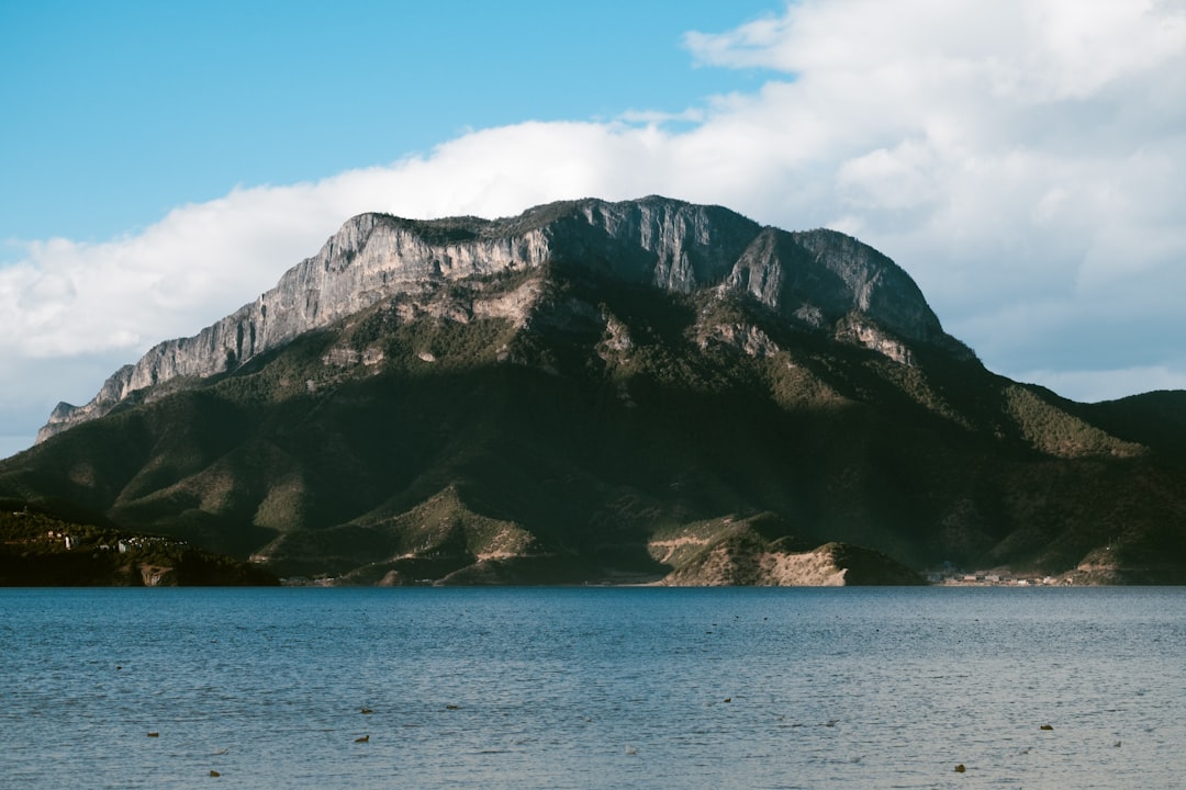 brown and green mountain beside body of water during daytime