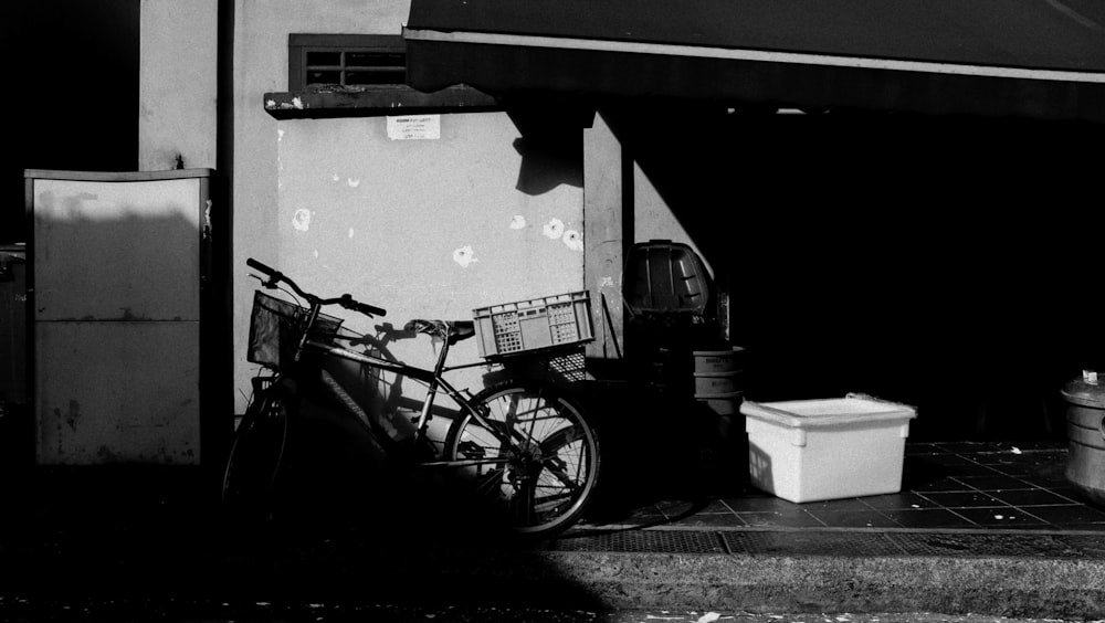 grayscale photo of bicycle parked beside wall