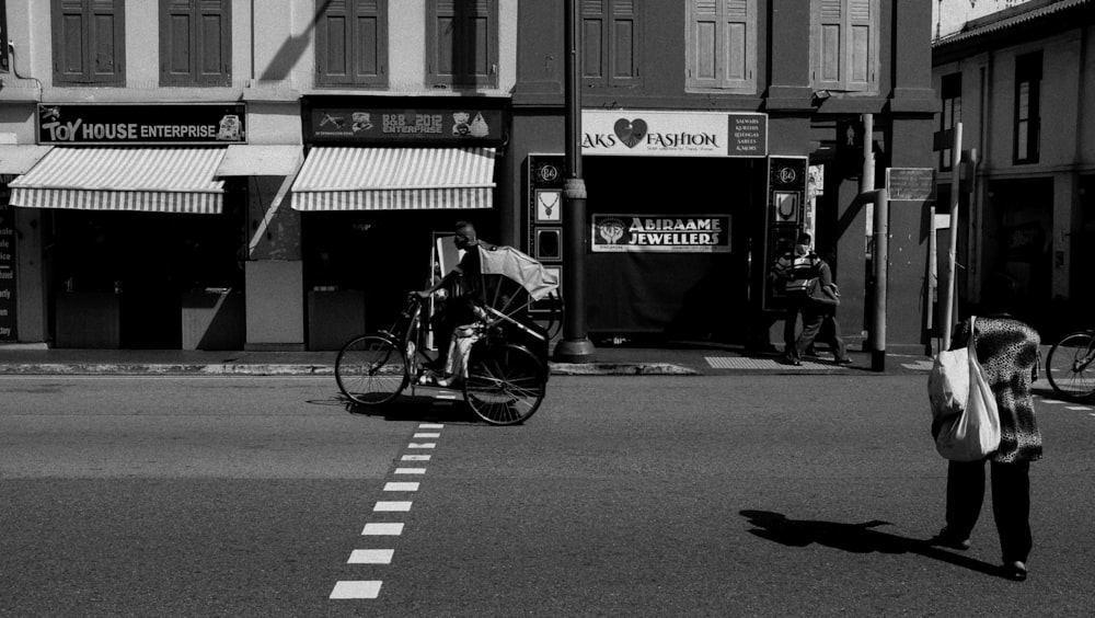 grayscale photo of man riding bicycle on road