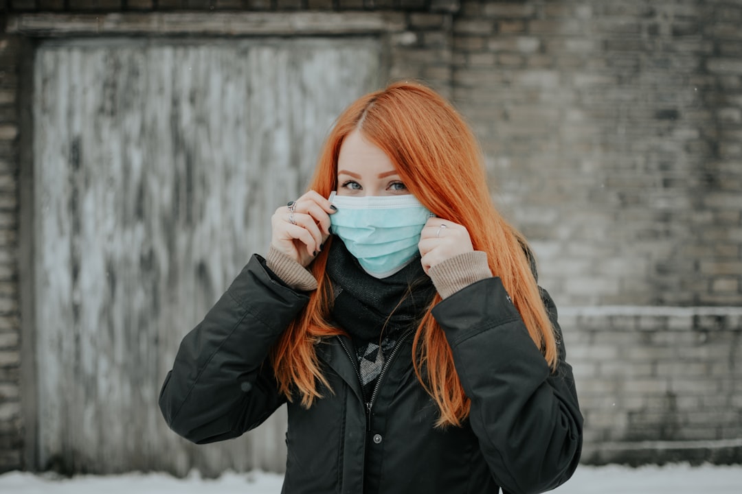 Auburn haired woman wearing a blue disposable face mask