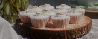 Close-up of colorful, beautifully decorated cupcakes arranged on a rustic wooden tray.