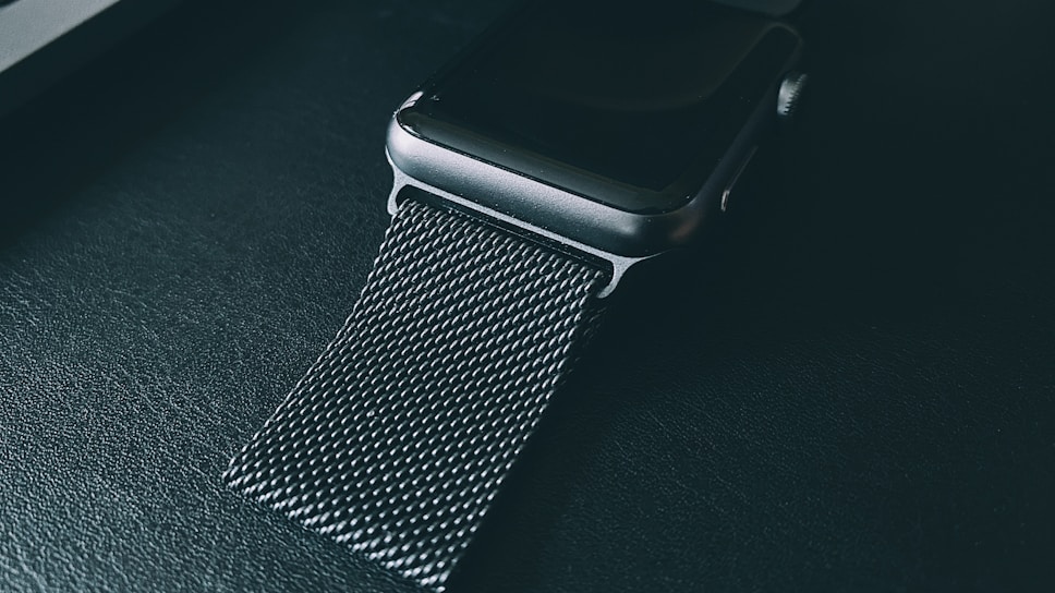 Close-up of a sleek Apple Watch with a vibrant sport band glowing under soft lighting.