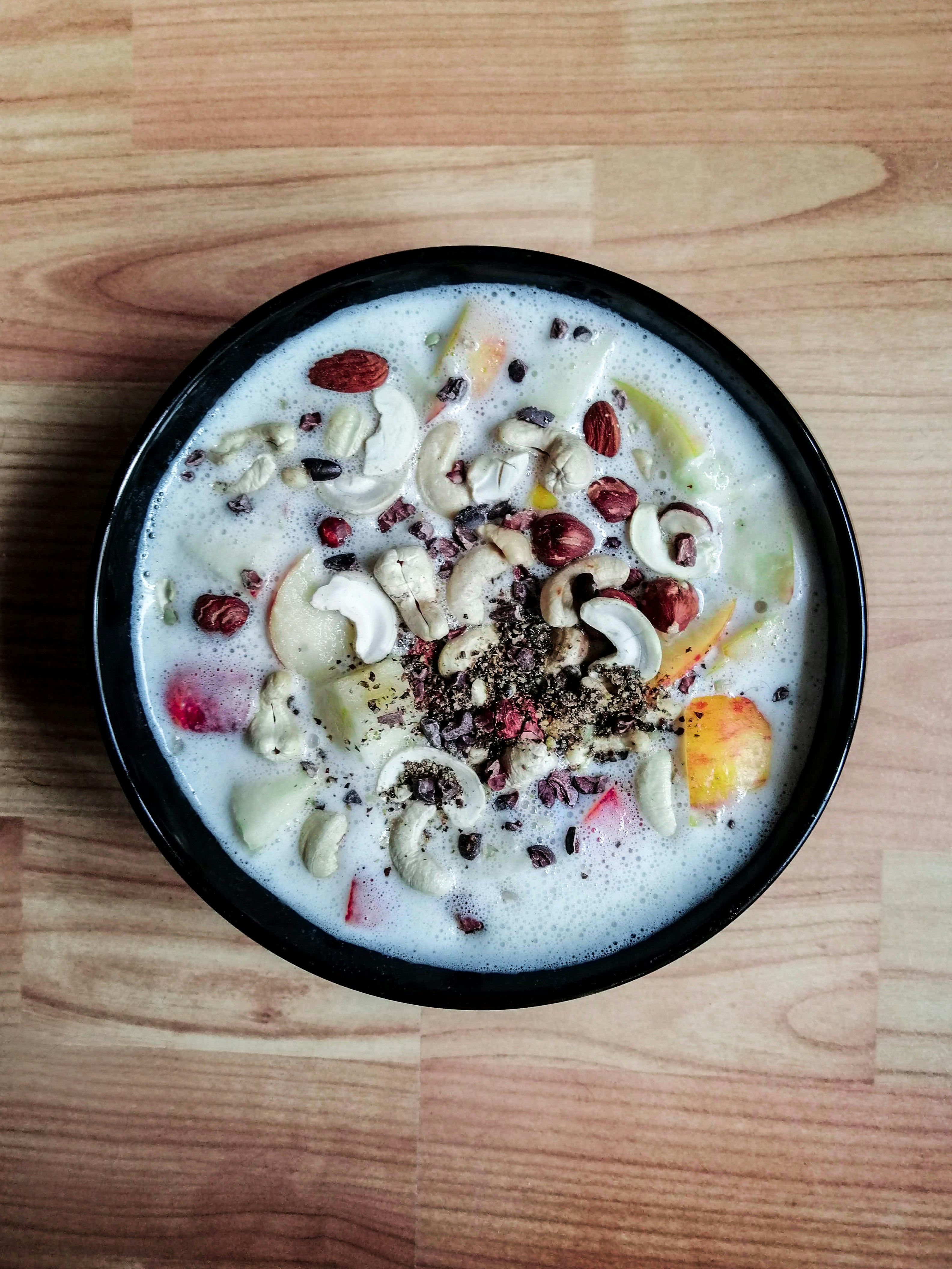 Yaourt naturel dans un bol blanc avec fruits frais sur table en bois, ambiance cuisine lumineuse