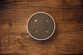 Close-up of a voice-activated smart speaker resting on a wooden kitchen counter.