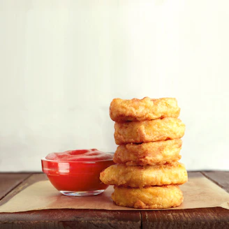 An inviting plate of golden onion rings stacked high with a side of dipping sauce.