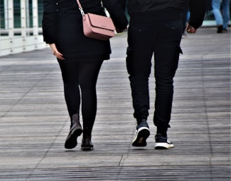 woman in black pants and black leather boots holding brown leather sling bag