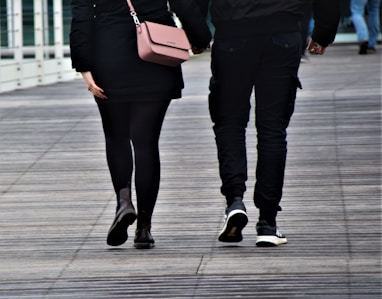 woman in black pants and black leather boots holding brown leather sling bag