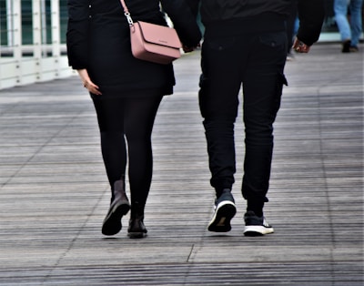 woman in black pants and black leather boots holding brown leather sling bag