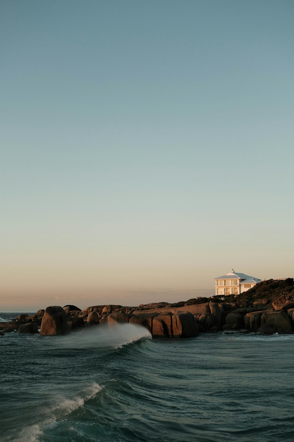 white and brown house on brown rock formation near body of water during daytime