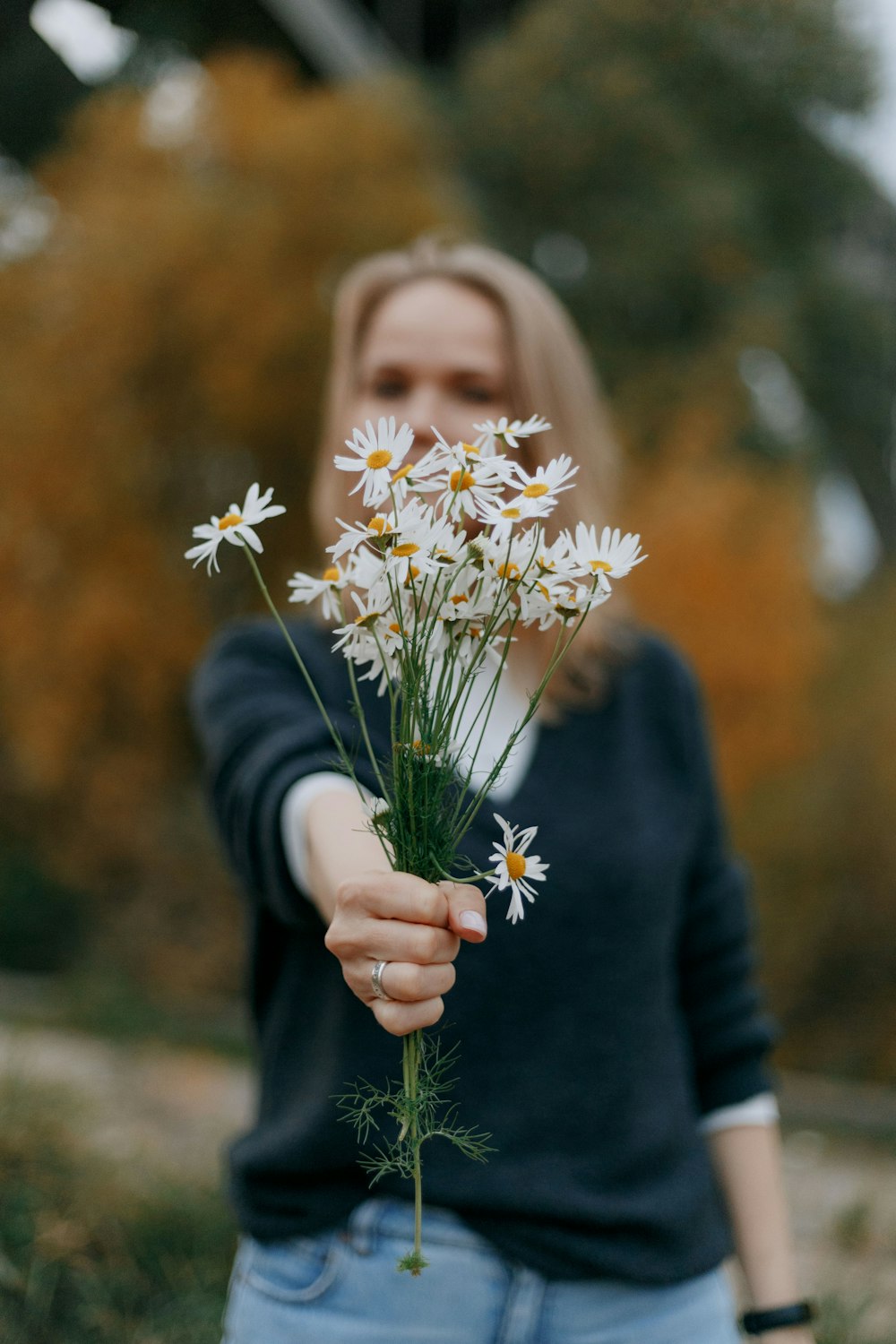 woman in black long sleeve shirt holding white and yellow flowers