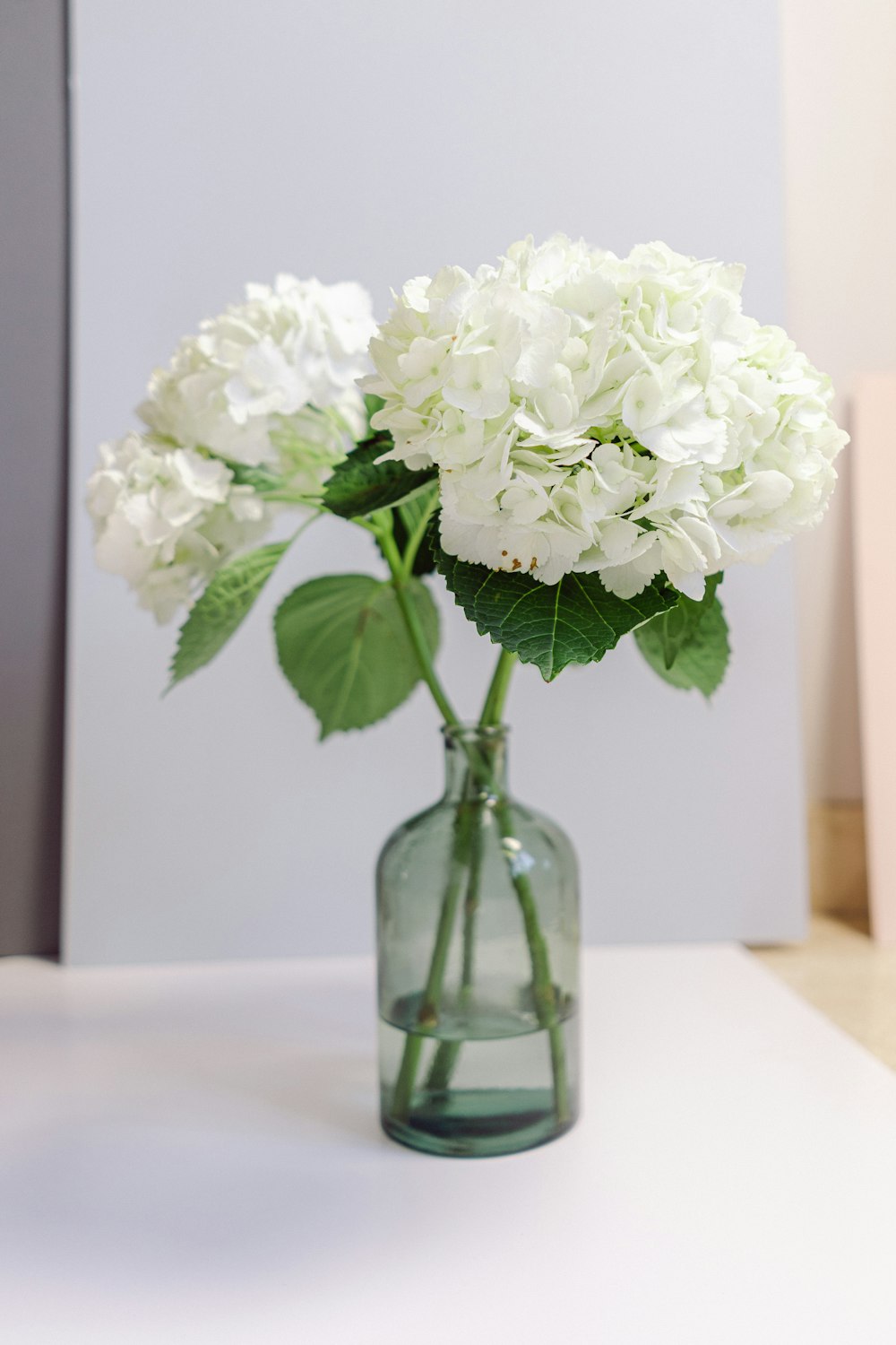 white flowers in green glass vase