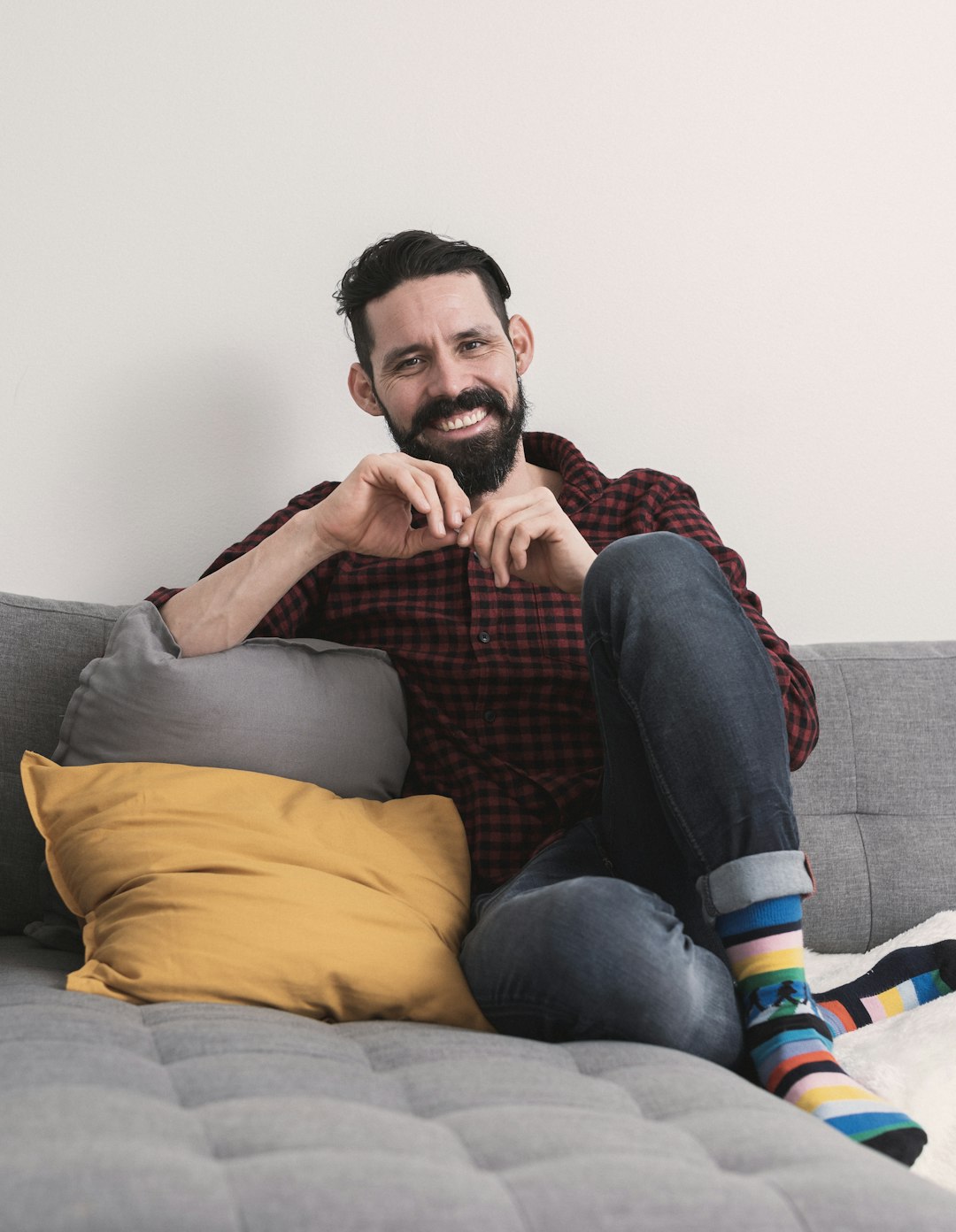 man in gray crew neck t-shirt and blue denim jeans sitting on gray sofa