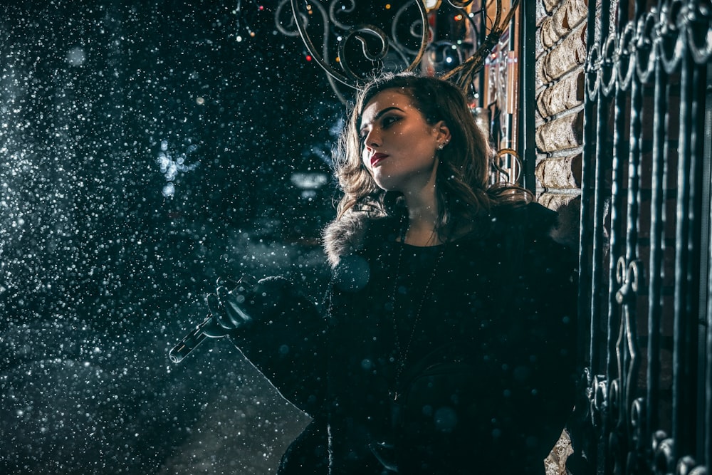 woman in black long sleeve shirt standing beside white string lights