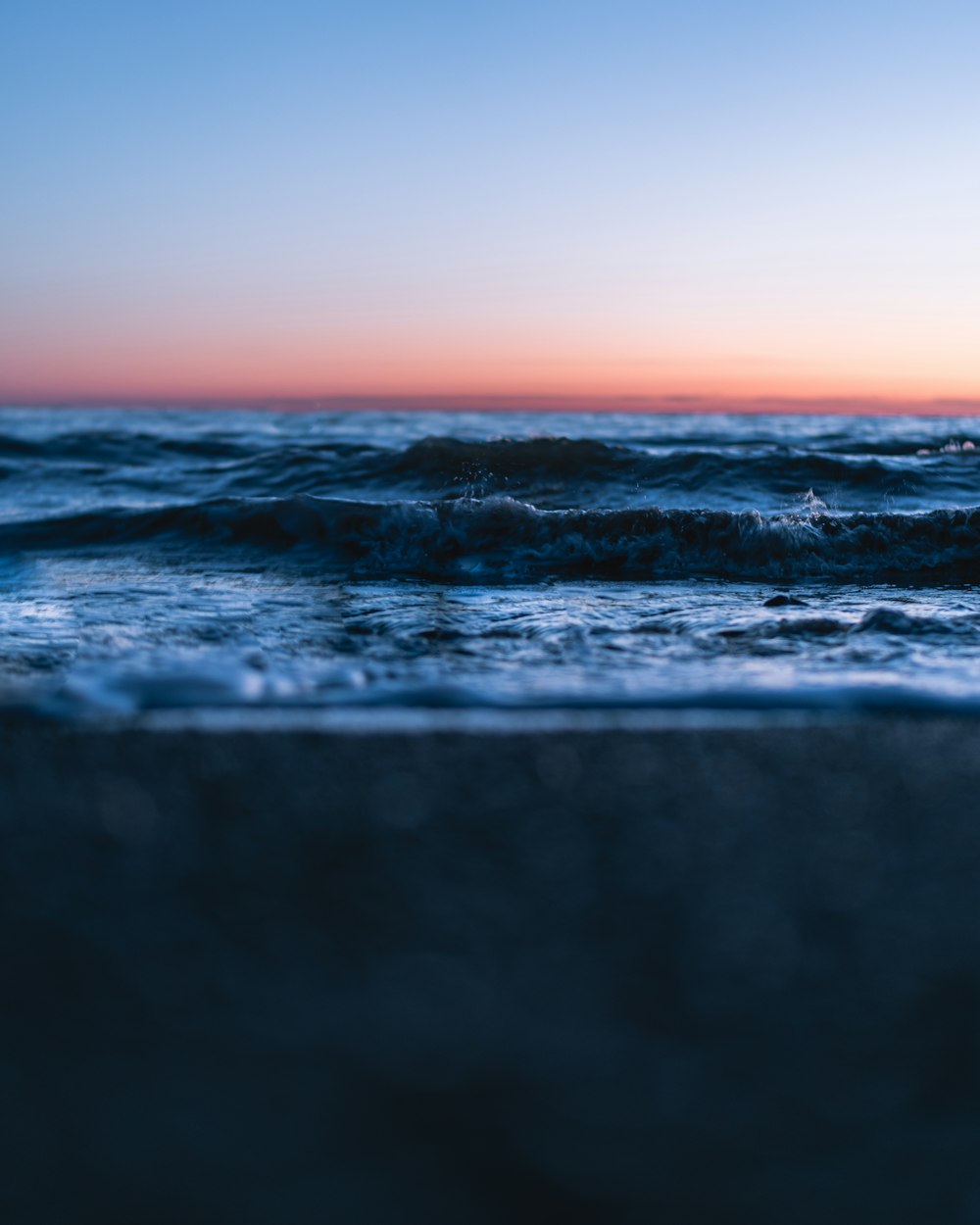 ocean waves crashing on shore during sunset