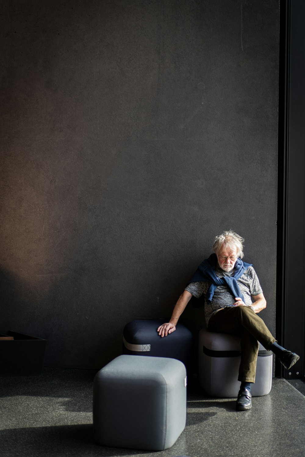 man in blue denim jacket sitting on black leather armchair