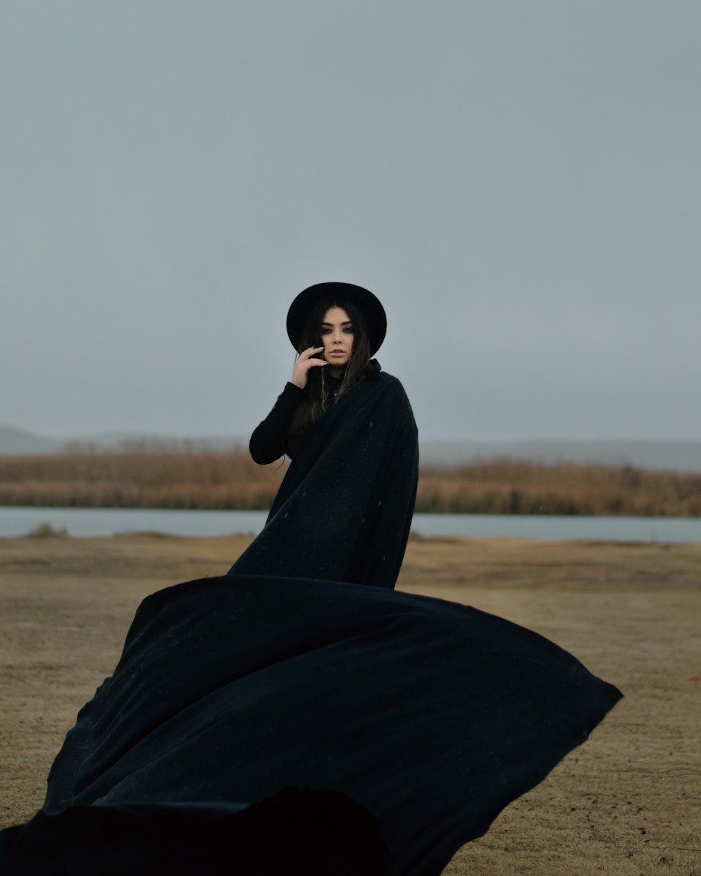 woman in black robe standing on brown field during daytime