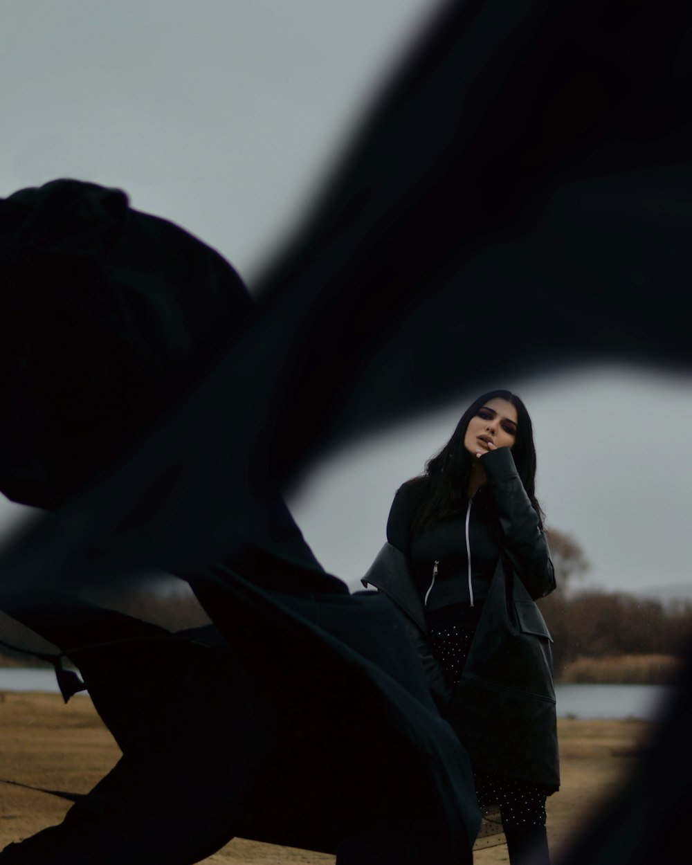 woman in black jacket and black pants sitting on brown field during daytime