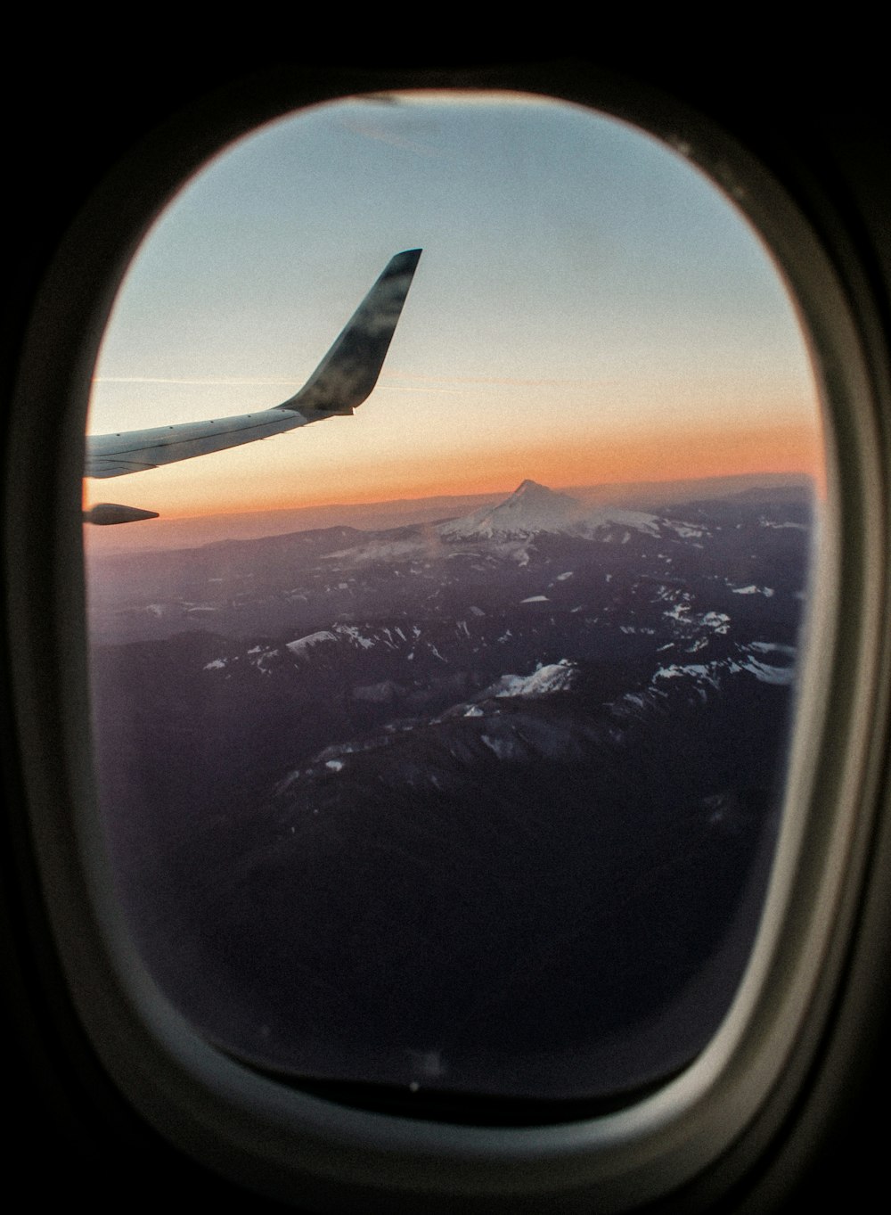 낮 동안 눈 덮인 산의 비행기 창 전망