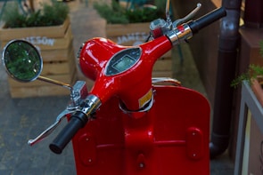 Close-up of a glossy red scooter’s intricate handlebar and dashboard details.