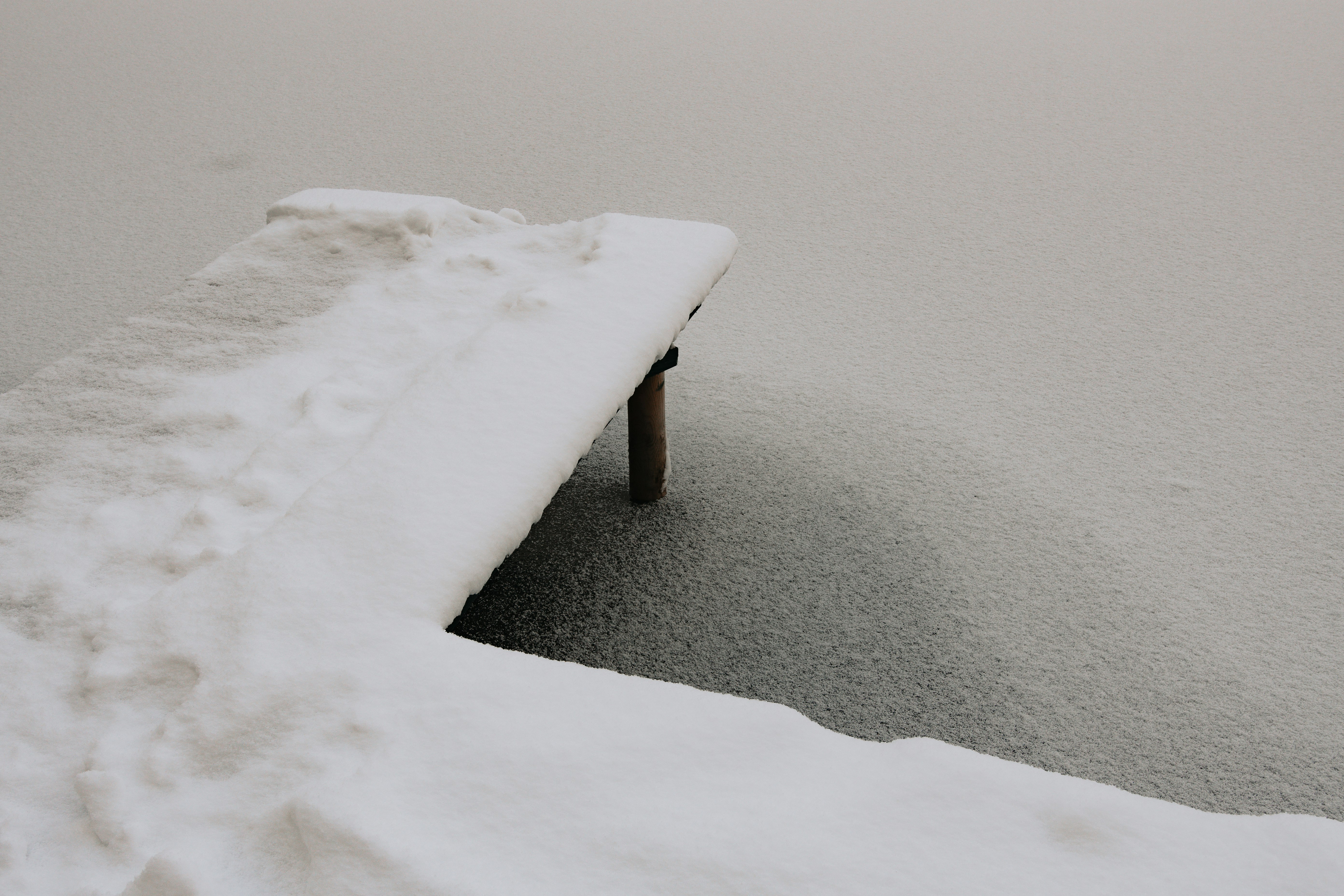 snow covered bench on snow covered ground