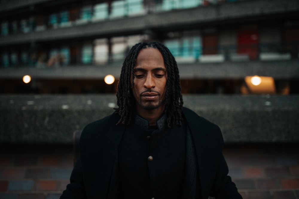 man in black coat standing near brown brick wall during daytime