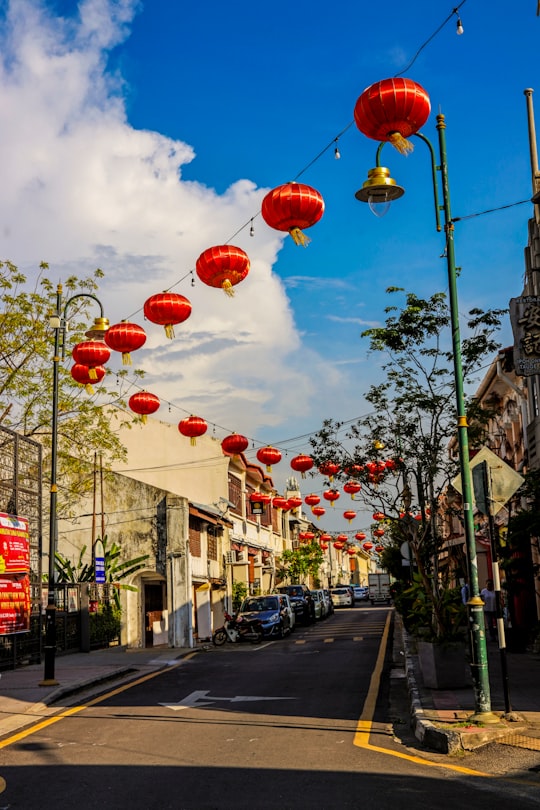 red and yellow lanterns on street during daytime in Penang Island Malaysia