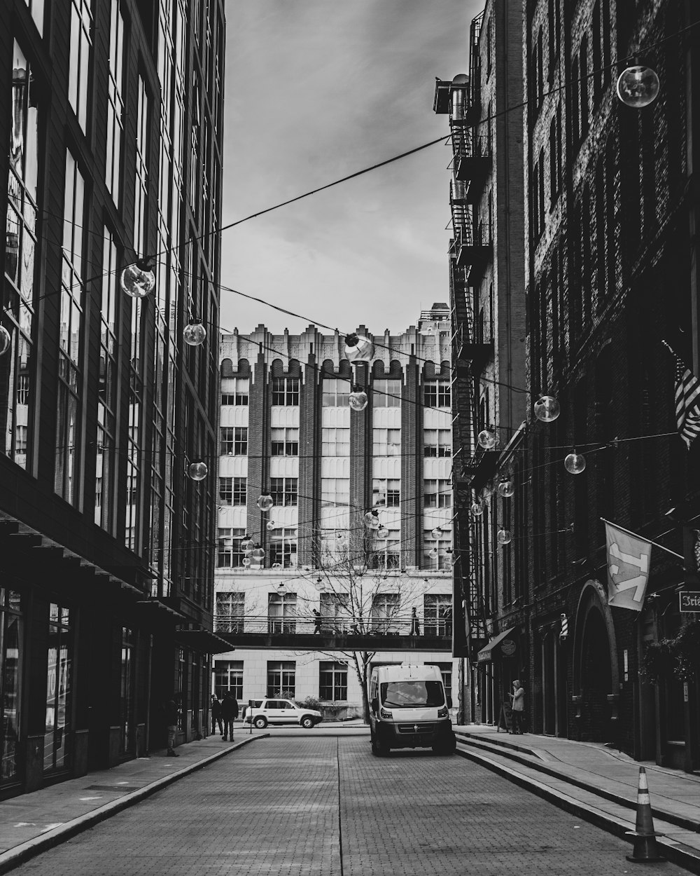 grayscale photo of cars on road between high rise buildings