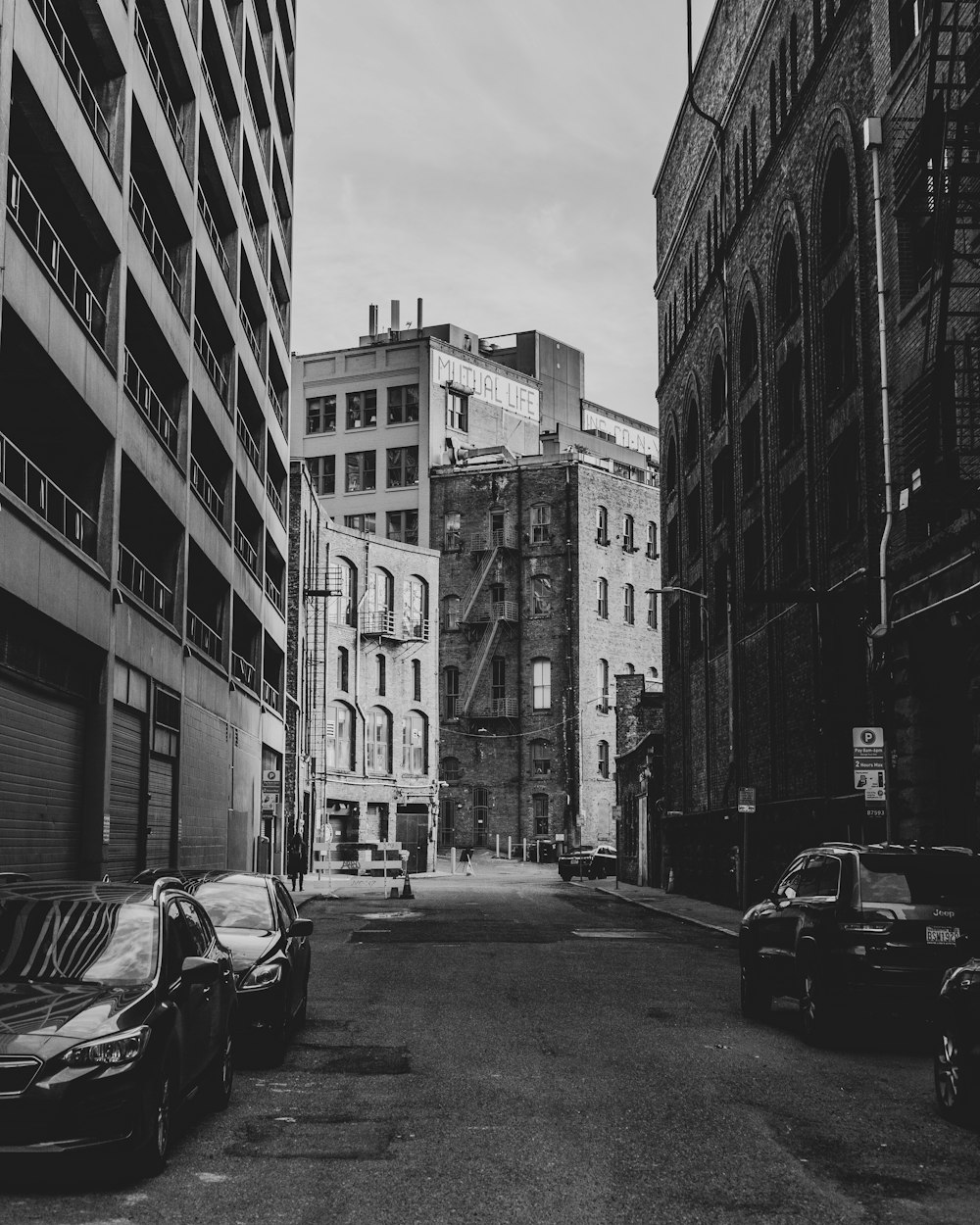 grayscale photo of cars parked on side of the road