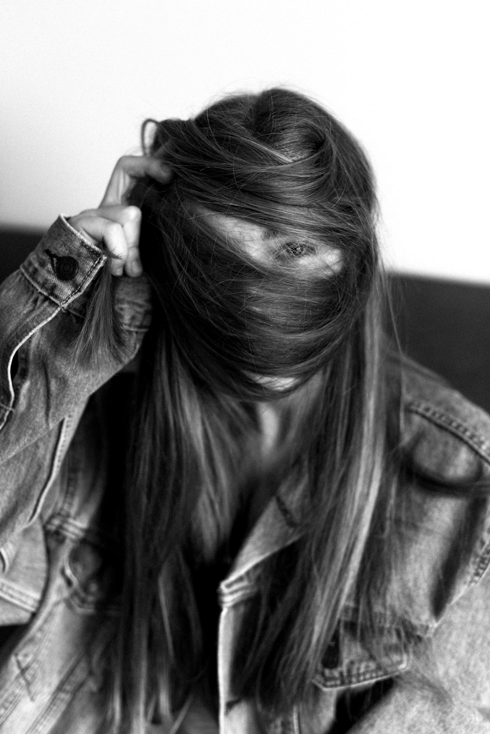 woman in denim jacket covering her face with her hair