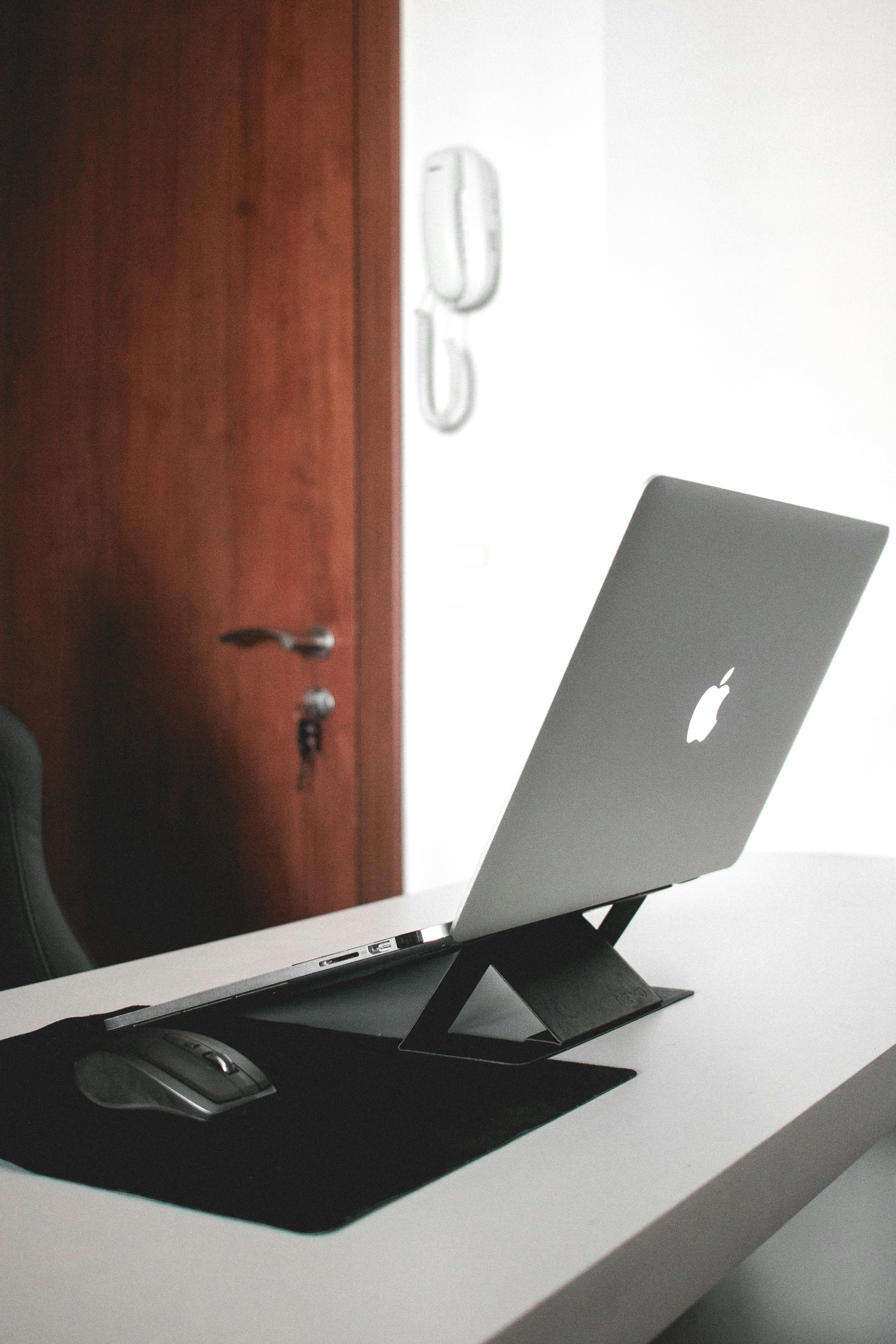 silver macbook on white table