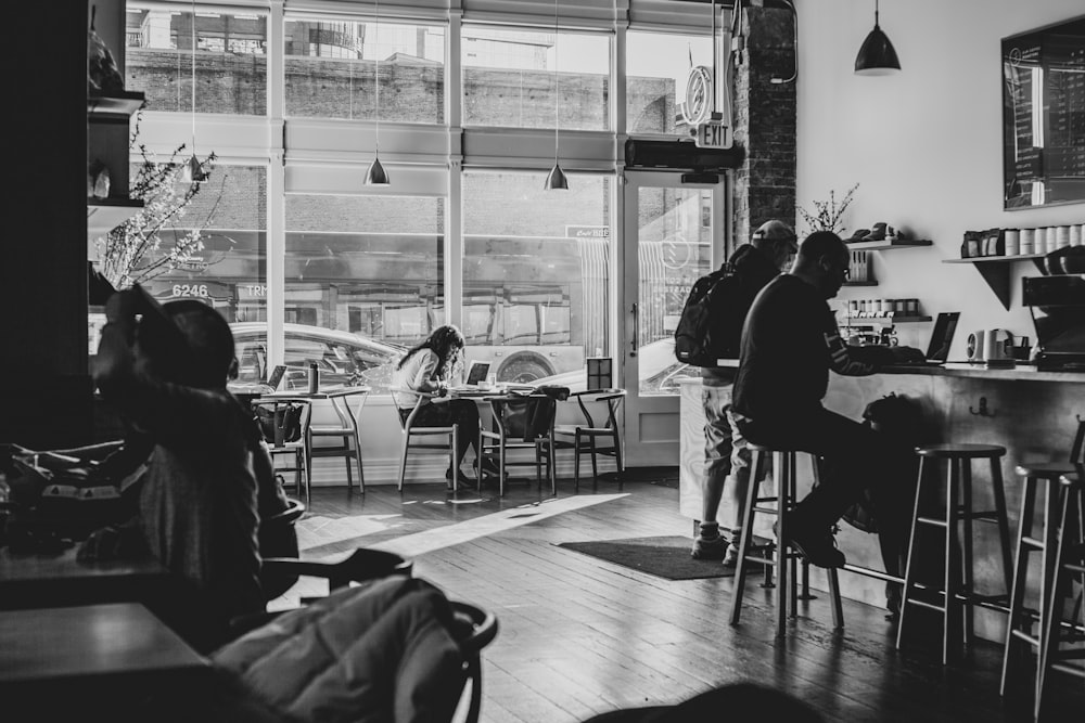 grayscale photo of people sitting on chair