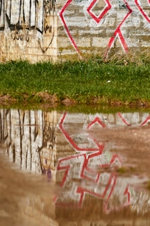 Before and after shots of a graffiti-covered wall cleaned by Unity Drainage Solutions team.
