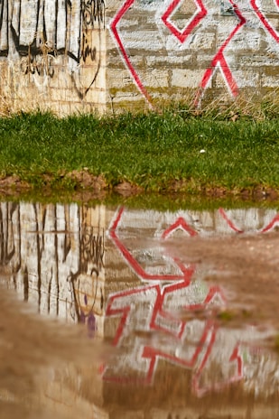 Before and after shots of a graffiti-covered wall cleaned by Unity Drainage Solutions team.