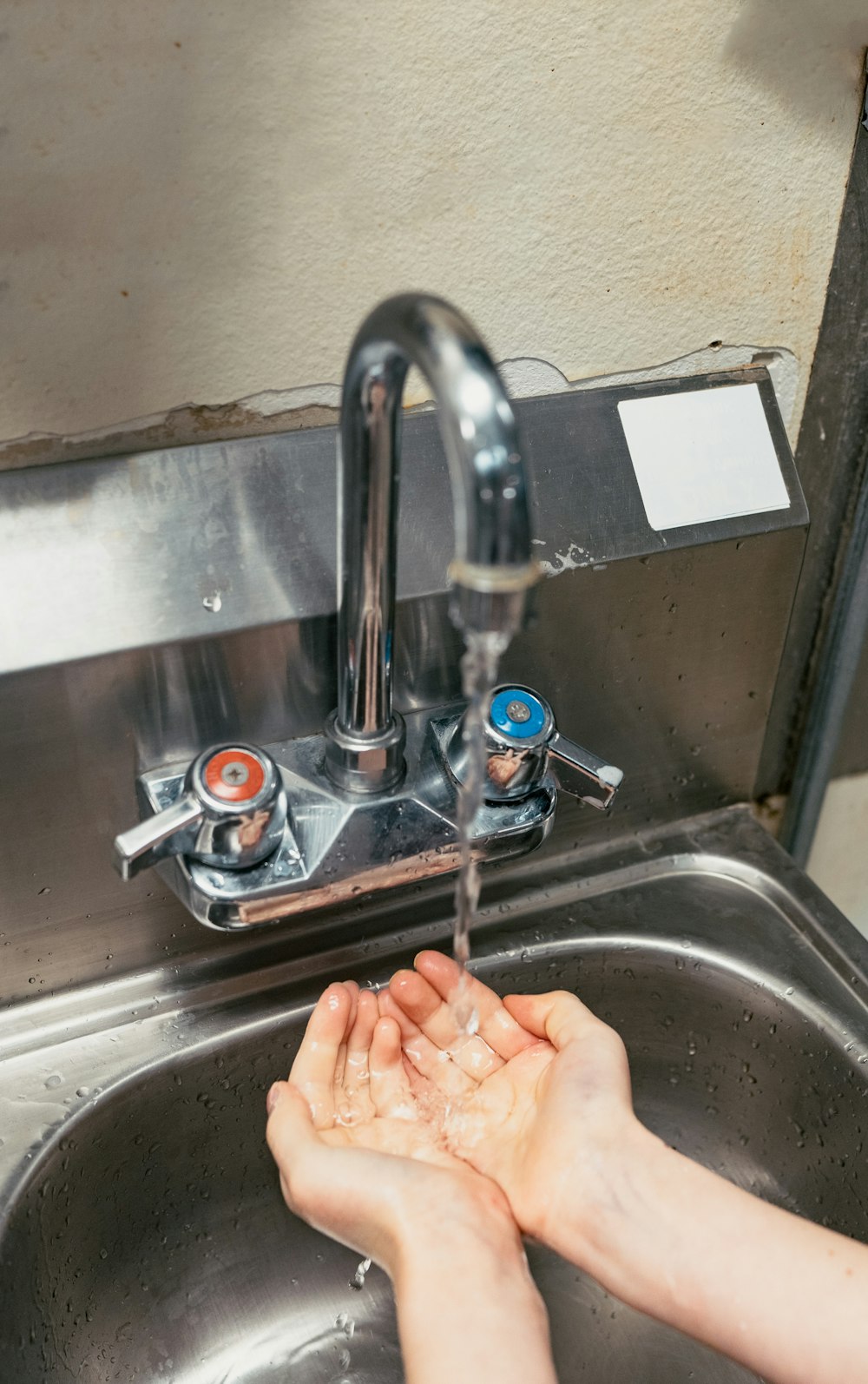 person washing hand on stainless steel faucet