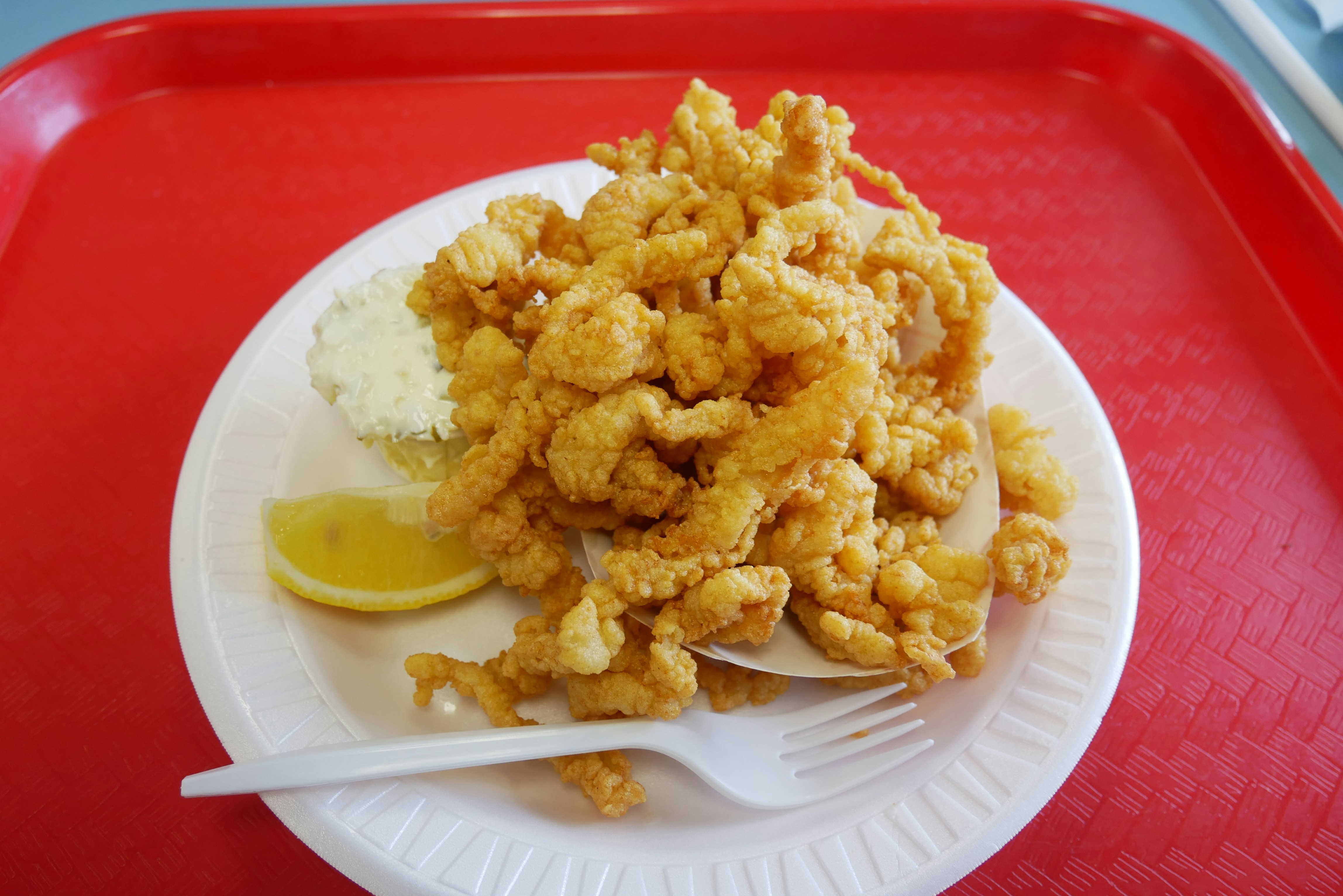 Basket of golden fried clams with lemon wedge and tartar sauce