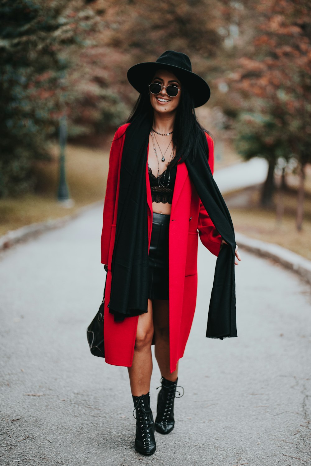 mulher no casaco vermelho de pé na estrada durante o dia