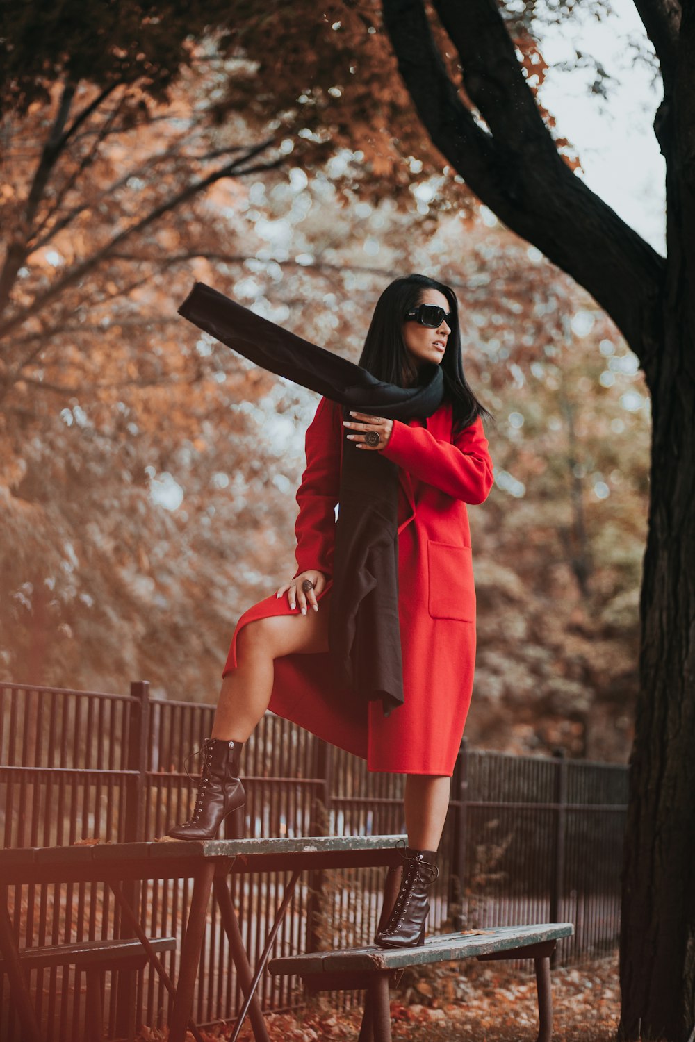 Mujer en vestido rojo de manga larga de pie junto a la valla de madera marrón durante el día